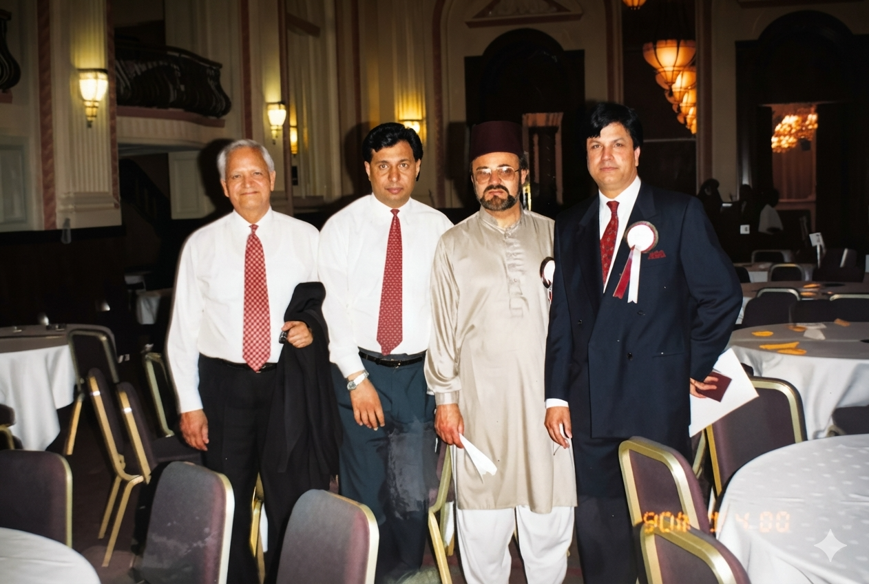 Four men, two wearing Academy rosettes, standing among banquet tables in a formal hall, November 1990.