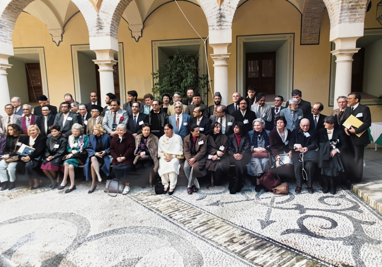 Delegates of an Academy conference posed in several rows in a colonnaded courtyard.